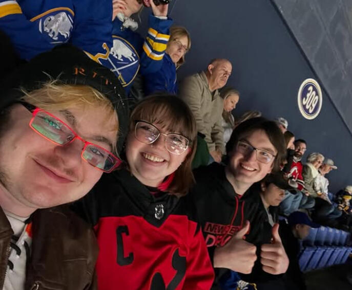 Lyle is taking a selfie with Liz and Elias seated behind/next to him in the frame