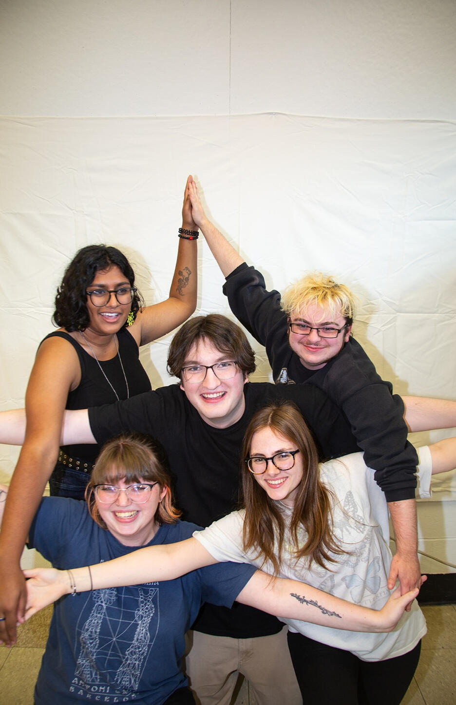 Lyle and four of his friends making a star with their arms, two people are standing in back, two are kneeling in front, and one is in the middle of everything to complete the star